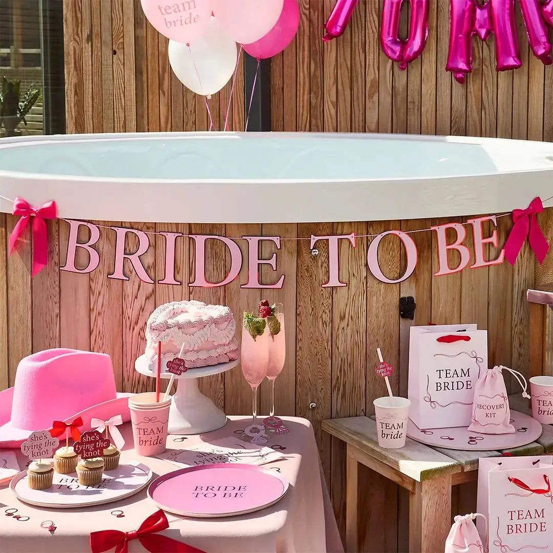 Styling a pink and red hen party with bow-themed napkins and metallic ring confetti